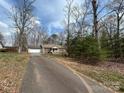 A cozy brick and siding home has a long driveway surrounded by mature trees at 1222 Hillsboro Ave, Hickory, NC 28602