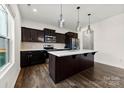 Modern kitchen features dark wood cabinets, stainless steel appliances, and an island with white countertop at 1976 Ethan Ln, Stanfield, NC 28163