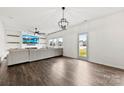 Open-concept living area with a large sectional, modern lighting, and a glass door to the yard at 1976 Ethan Ln, Stanfield, NC 28163