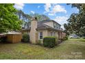 Charming home featuring a brick chimney, manicured landscaping, and a covered front porch adorned with an American flag at 6807 Stoney Ridge Rd, Matthews, NC 28104