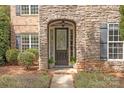 Elegant front door framed by stone, complemented by black shutters and lush greenery at 11308 Wheat Ridge Rd, Charlotte, NC 28277