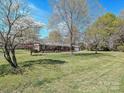 A beautiful, tree-lined property showcases a classic brick ranch-style home with a spacious front yard at 12300 Eva St, Matthews, NC 28105