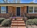 Inviting brick entryway with decorative black door, accented by potted flowers and classic black railings at 12300 Eva St, Matthews, NC 28105