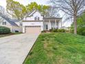 Traditional home with a beige garage door, charming porch, and well-maintained lawn at 12708 Hollyhock Ln, Huntersville, NC 28078