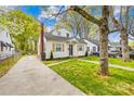 Classic home features a green lawn, a driveway leading to the side of the house, and mature trees at 1409 Effingham Rd, Charlotte, NC 28208