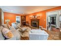 Comfortable living room with cozy seating, fireplace, hardwood floors, and warm, orange walls at 1529 S Wendover Rd, Charlotte, NC 28211