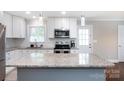Modern kitchen featuring granite countertops, stainless steel appliances, white cabinetry, and hardwood floors at 2408 Dora Dr, Charlotte, NC 28215