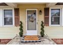Close-up of the front door with decorative plants, a welcome mat, and classic exterior finishes at 325 Hurley School Rd, Salisbury, NC 28147