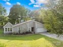 Attractive home featuring a stone accent wall, an attached two-car garage, a bright green lawn, and mature trees at 6741 Stillmeadow Dr, Charlotte, NC 28277