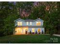 Charming two-story gray home with a manicured front lawn and brick foundation under the porch in a wooded lot at 8021 Willhill Rd, Mint Hill, NC 28227