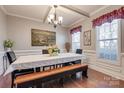 Cozy dining area with natural light, wainscoting, hardwood floors, and a contemporary chandelier at 10728 Bere Island Dr, Charlotte, NC 28278
