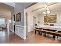 Elegant dining room boasts hardwood floors, detailed molding, coffered ceiling, and stylish chandelier at 10728 Bere Island Dr, Charlotte, NC 28278