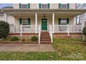 Inviting front porch with white railing, green door and shutters, and brick stairs at 11415 Serenity Way, Charlotte, NC 28269