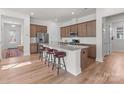 Open kitchen with center island with seating, stainless appliances, hardwood floors, and pendant lights with a view to entry at 12110 Anne Blount Aly, Huntersville, NC 28078