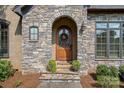 Elegant stone entryway with arched doorway and beautifully stained wood door at 1407 Becklow Ct, Wesley Chapel, NC 28079