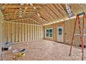 A view of the framed living room with a high ceiling, exposed wooden beams, and natural light from the windows at 2508 Rock Dam Rd, Lincolnton, NC 28092