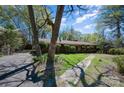 Features an angle shot of a brick home with a stone walkway, complemented by a tidy lawn and mature trees under a blue sky at 340 Sardis N Rd, Charlotte, NC 28270