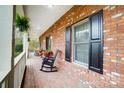 Inviting brick front porch with rocking chairs, black shutters, and manicured hedges at 361 Nance Rd, Stanfield, NC 28163
