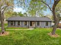 Traditional single-story home with a beautiful green lawn, tasteful shutters, and mature trees providing shade at 7009 Wrentree Dr, Charlotte, NC 28210