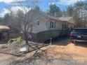 The side of a ranch style home with light colored siding, a driveway, landscaping and a dark SUV at 7122 Pyramid Rd, Hickory, NC 28602
