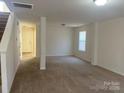 Open-concept living space showcasing neutral walls, carpet flooring, and a convenient stairway access at 104 Mulligan Dr, Shelby, NC 28150