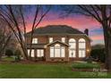 Brick home's rear view features a patio, large windows, and a spacious, well-maintained lawn at 10809 Wicklow Brook Ct, Charlotte, NC 28277