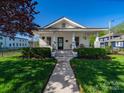 Inviting home with a well-maintained lawn, sidewalk, and classic front porch with decorative plantings at 1114 Herrin Ave, Charlotte, NC 28205