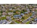 An aerial view showcases a stately home nestled within a neighborhood with mature trees and a pond at 11236 Mcclure Manor Dr, Charlotte, NC 28277