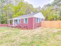 A charming red brick home is set back from the road with a large yard and a newly constructed wooden fence at 129 Wilson St, Chester, SC 29706