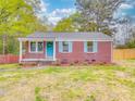 Charming red brick home with a bright blue front door and matching shutters, nestled in a lush green yard at 129 Wilson St, Chester, SC 29706