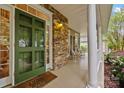 Inviting front porch featuring stone accents, rocking chairs, and a bright green front door at 17301 Glassfield Dr, Huntersville, NC 28078