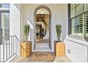 Inviting front entrance with arched doorway, potted plants, and a 'Welcome' mat on the covered porch at 318 Montrose Dr, Waxhaw, NC 28173