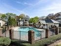 Community pool surrounded by a fence, greenery, and nearby buildings at 5007 Sharon Rd # S, Charlotte, NC 28210