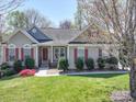 Charming home featuring a well-manicured lawn and red shutters enhancing its curb appeal on a sunny day at 7524 Common Oak Dr, Stanley, NC 28164