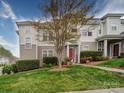 Exterior view of townhome with manicured lawn, mature tree, and covered entrance at 920 Ashworth Dr, Gastonia, NC 28054