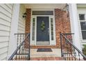 Welcoming front entrance with brick accents, black railing, and decorative wreath on the door at 11333 Snapfinger Dr, Charlotte, NC 28277