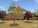 Elegant brick home showcasing a lush front yard, mature trees, and classic architectural details at 130 Villa Lake Dr, Fort Mill, SC 29708