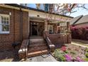 Inviting brick home showcasing a cozy front porch, manicured landscaping and vibrant flowerbeds at 139 S Laurel Ave, Charlotte, NC 28207