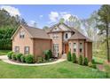 A view of a large brick home with a green lawn, trees, and attractive landscaping at 164 Crooked Branch Way, Troutman, NC 28166
