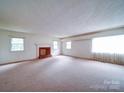 Bright living room featuring a decorative fireplace, carpet flooring, and multiple windows at 167 Cedar Ln, Troutman, NC 28166