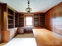 Wood-paneled home office featuring built-in bookshelves, cabinets, drawers, and a large desk at 167 Cedar Ln, Troutman, NC 28166