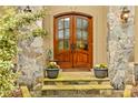 Inviting entryway with double wooden doors, stone accents, and decorative potted plants at 19040 Mary Ardrey Cir, Cornelius, NC 28031