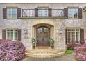 Grand stone entrance showcasing an arched doorway, double doors, elegant lighting, and landscaped foliage at 20635 Queensdale Dr, Cornelius, NC 28031