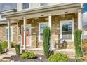 Inviting front porch featuring stone accents, quaint seating, and a welcoming coral-colored front door at 2222 Smoltz Dr, Rock Hill, SC 29730