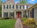 Inviting front entrance with a red door, complemented by lush landscaping and classic architectural details at 2812 Edgebrook Cir, Matthews, NC 28105