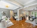 A well decorated living room with hardwood floors, gray wallpaper accent wall, and adjoining seating areas at 8912 Heydon Hall Cir, Charlotte, NC 28210