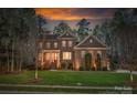 Dusk view of a charming brick two-story home with landscaped yard and warm exterior lighting at 10823 Preservation Park Dr, Charlotte, NC 28214