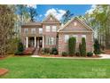 Charming brick two-story home with manicured lawn, stately columns, and mature trees at 10823 Preservation Park Dr, Charlotte, NC 28214