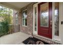 Covered front porch with brick siding and decorative glass front door at 10823 Preservation Park Dr, Charlotte, NC 28214