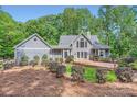 Rear exterior of the house features a wooden deck, lush landscaping, and a shingled facade in a wooded setting at 119 Taylor Ct, Mooresville, NC 28117